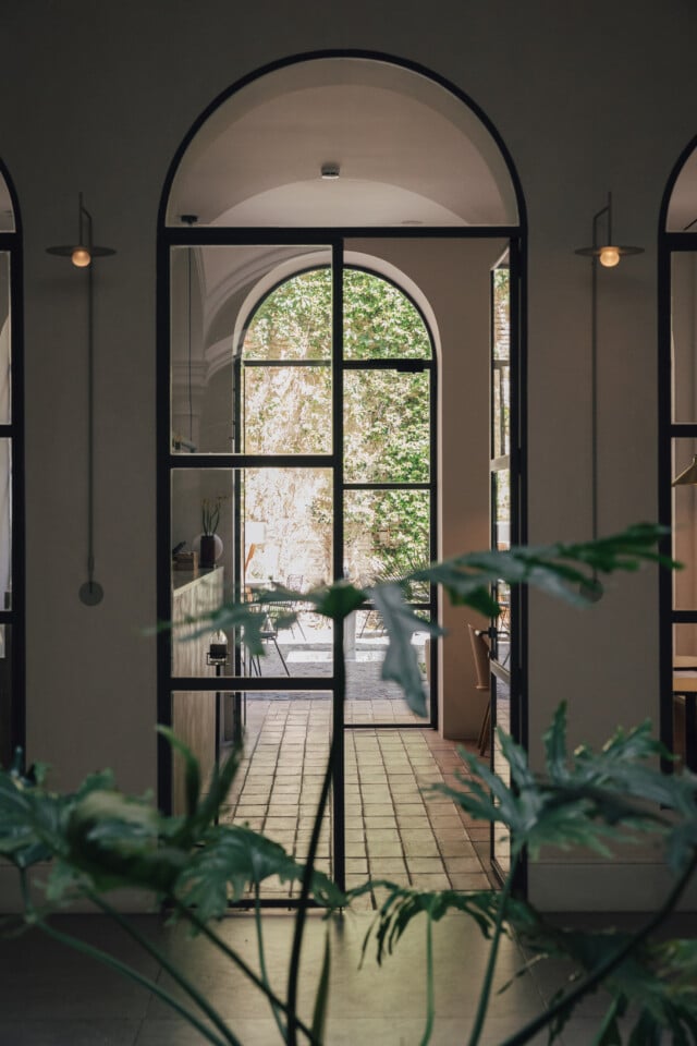 Pasillo interior del hotel Plácido y Grata con arco, luz natural y plantas que conectan el espacio con el patio.