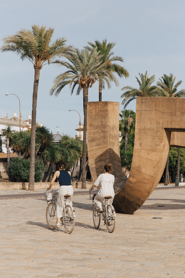 Dos personas recorren Sevilla en bicicleta a pocos pasos del hotel boutique Plácido y Grata.